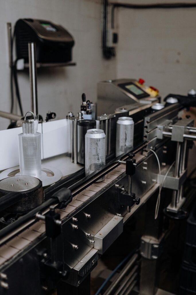 Beverage cans being processed on a conveyor belt in a production facility, showcasing automated machinery for filling and packaging.