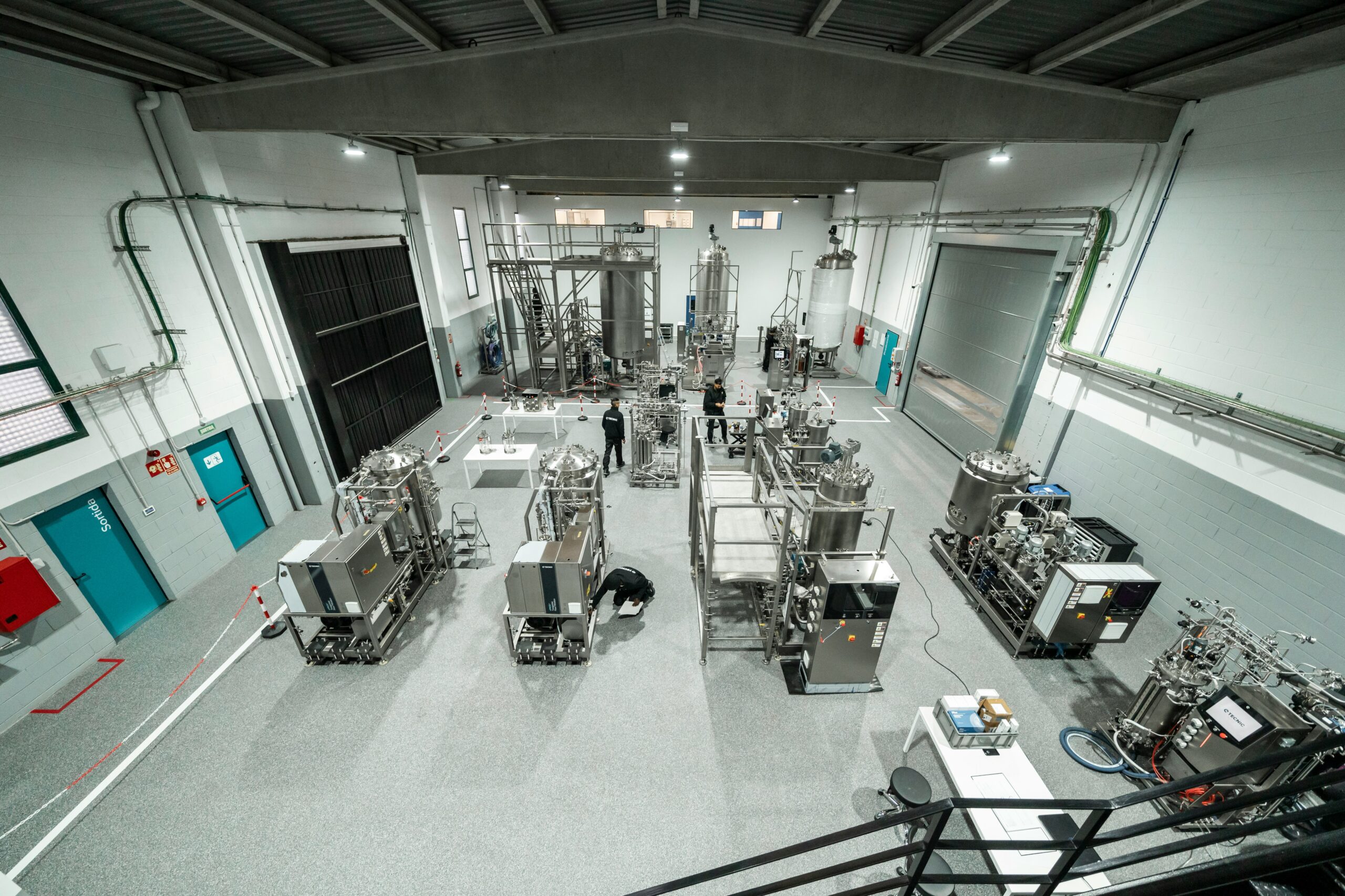 Laboratory interior featuring various stainless steel processing equipment and technicians working, showcasing advanced research capabilities.